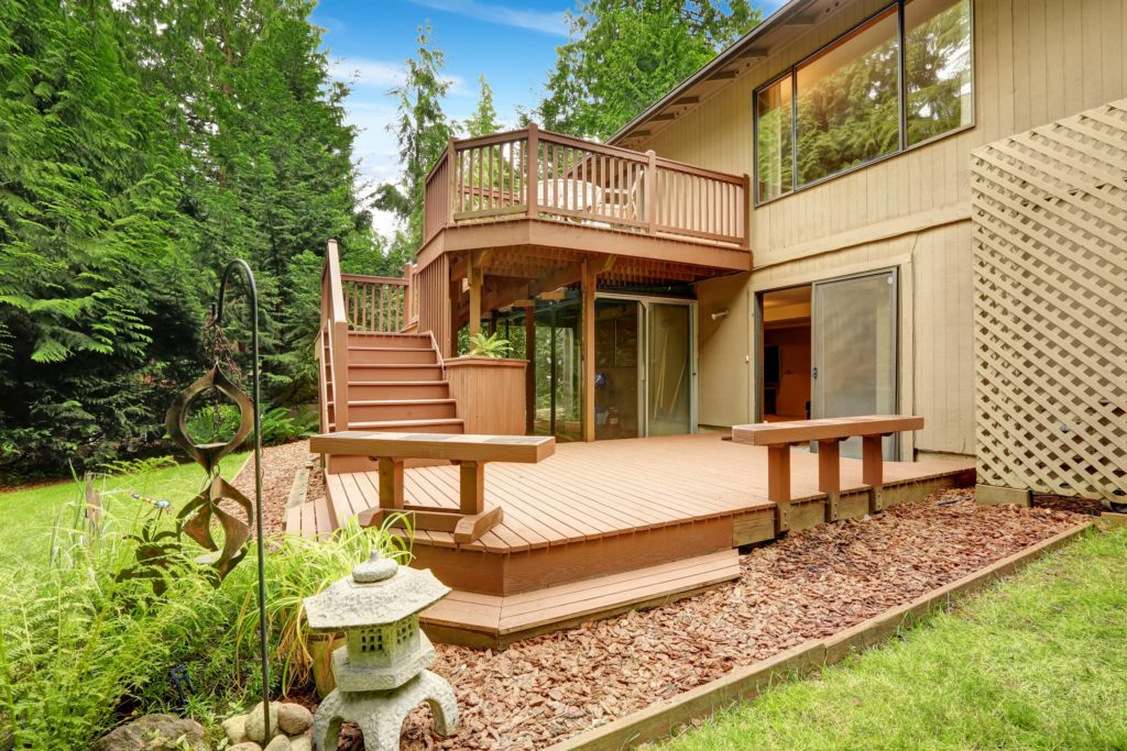 A picture of a large multi level deck with benches in the back yard of a house.