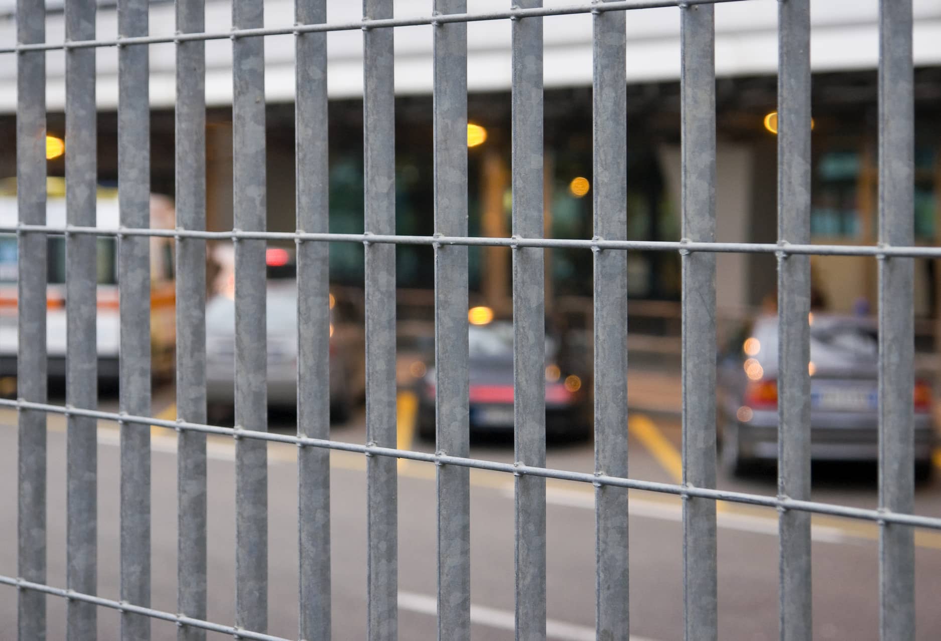 This picture shows a metal fence surrounding a commercial parking lot area.