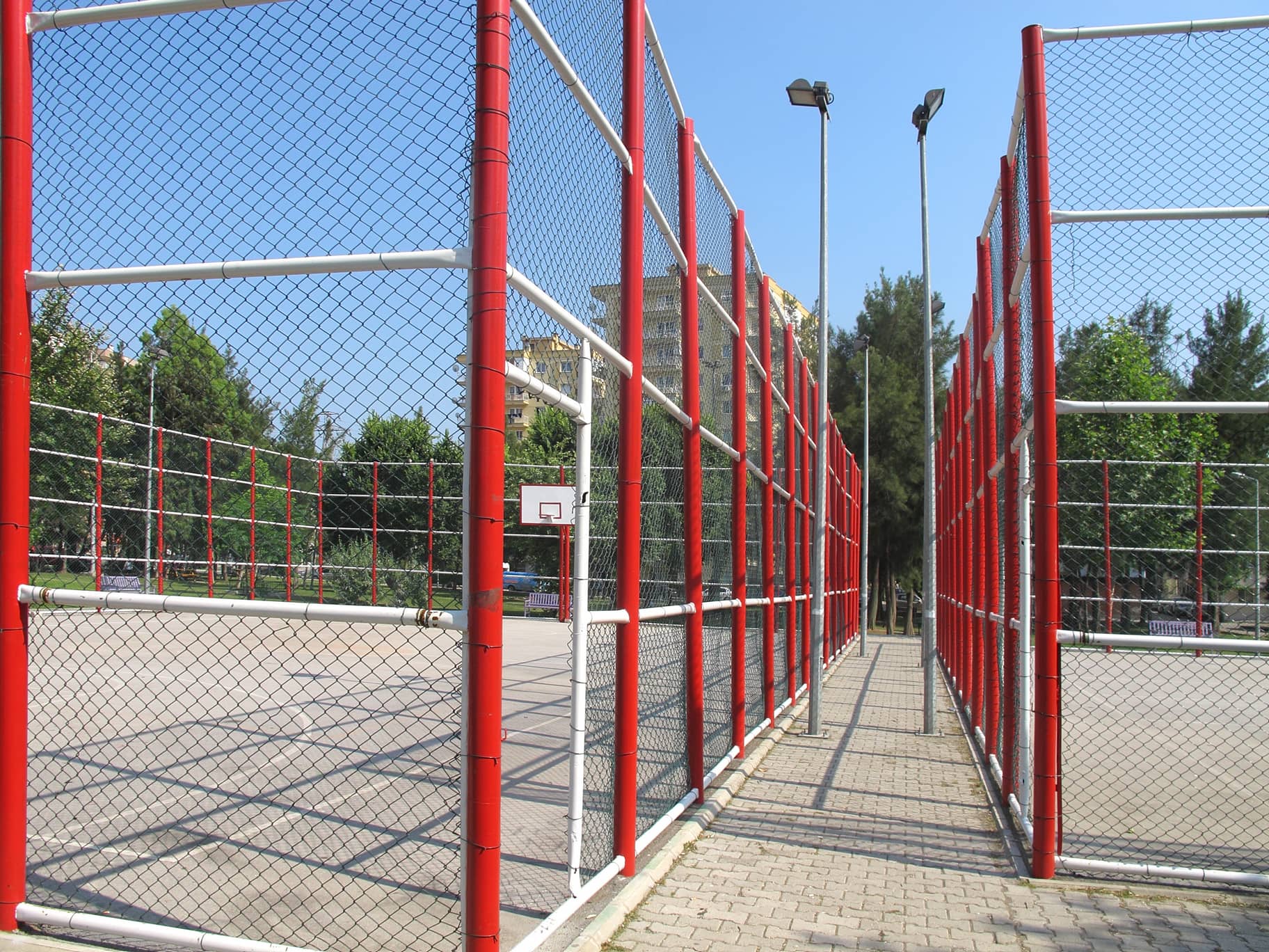 An image of metal fencing surrounding a basket ball court.
